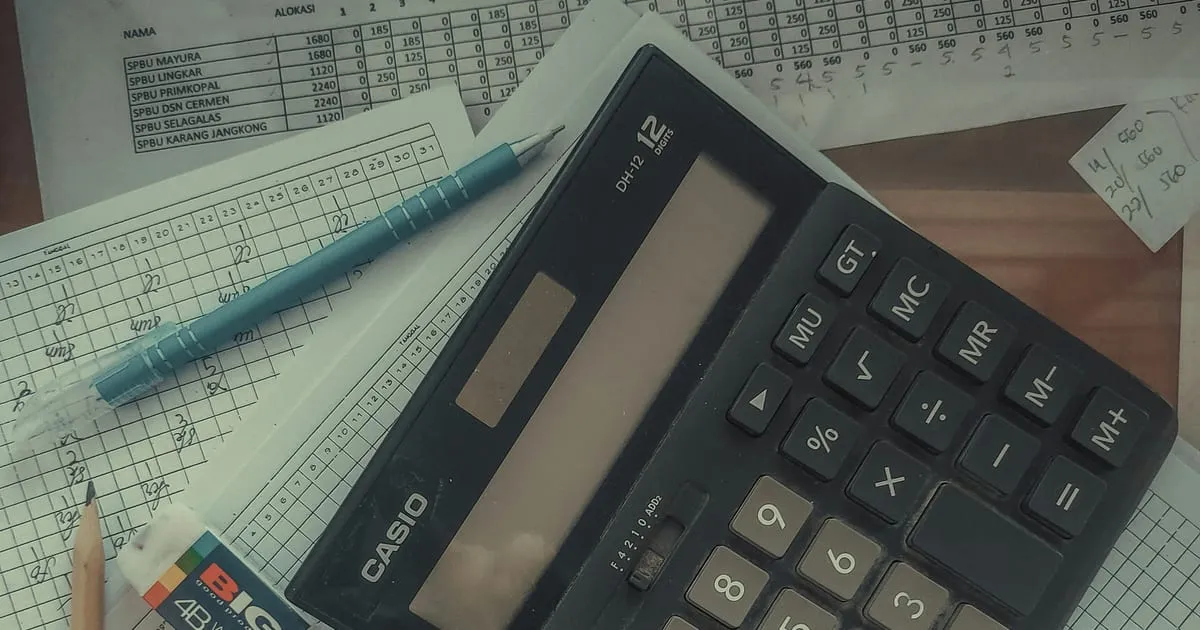 Calculadora sobre uma pilha de planilhas e papéis com anotações